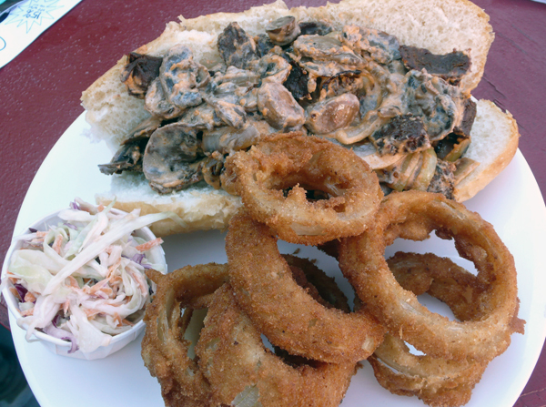philly cheesesteak: strips of beef smothered in vegan cheese piled with green onions, peppers and mushrooms. served with homemade onion rings. $8.95